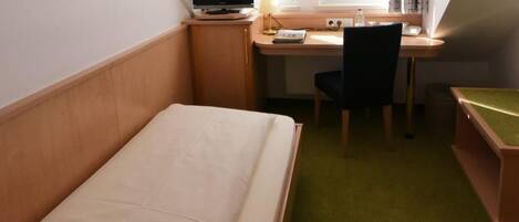 A hotel room with a bed, desk, chair, and a television.