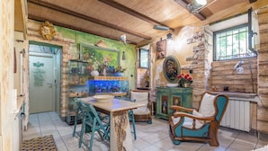 Eine gemütliche Küche mit Essbereich, mit Holzbalkendecke, Steinwänden und einem großen Aquarium.