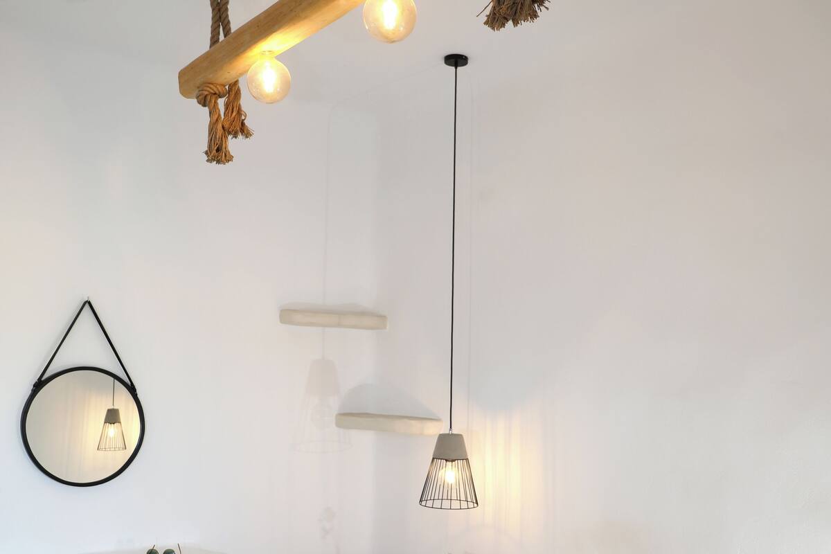 A bedroom with a bed, a desk, and a chair. There are two pendant lights and a wall-mounted light fixture.