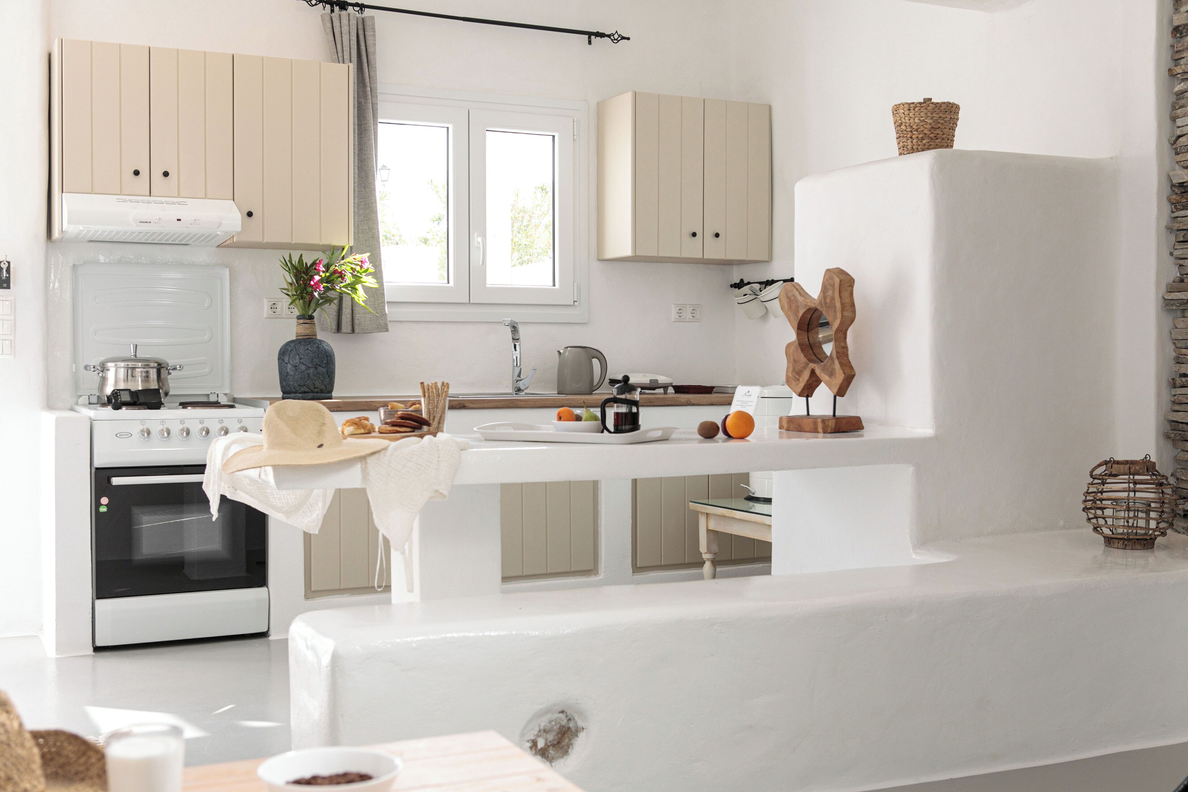 A modern kitchen with white cabinets, a built-in oven, and a dining area with a bench.