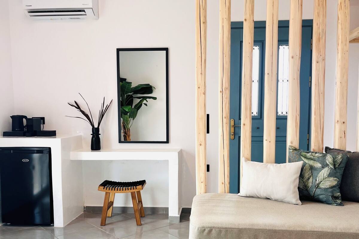 A modern living room with a sofa, a coffee table, a small wooden stool, a plant, and a framed picture on the wall.