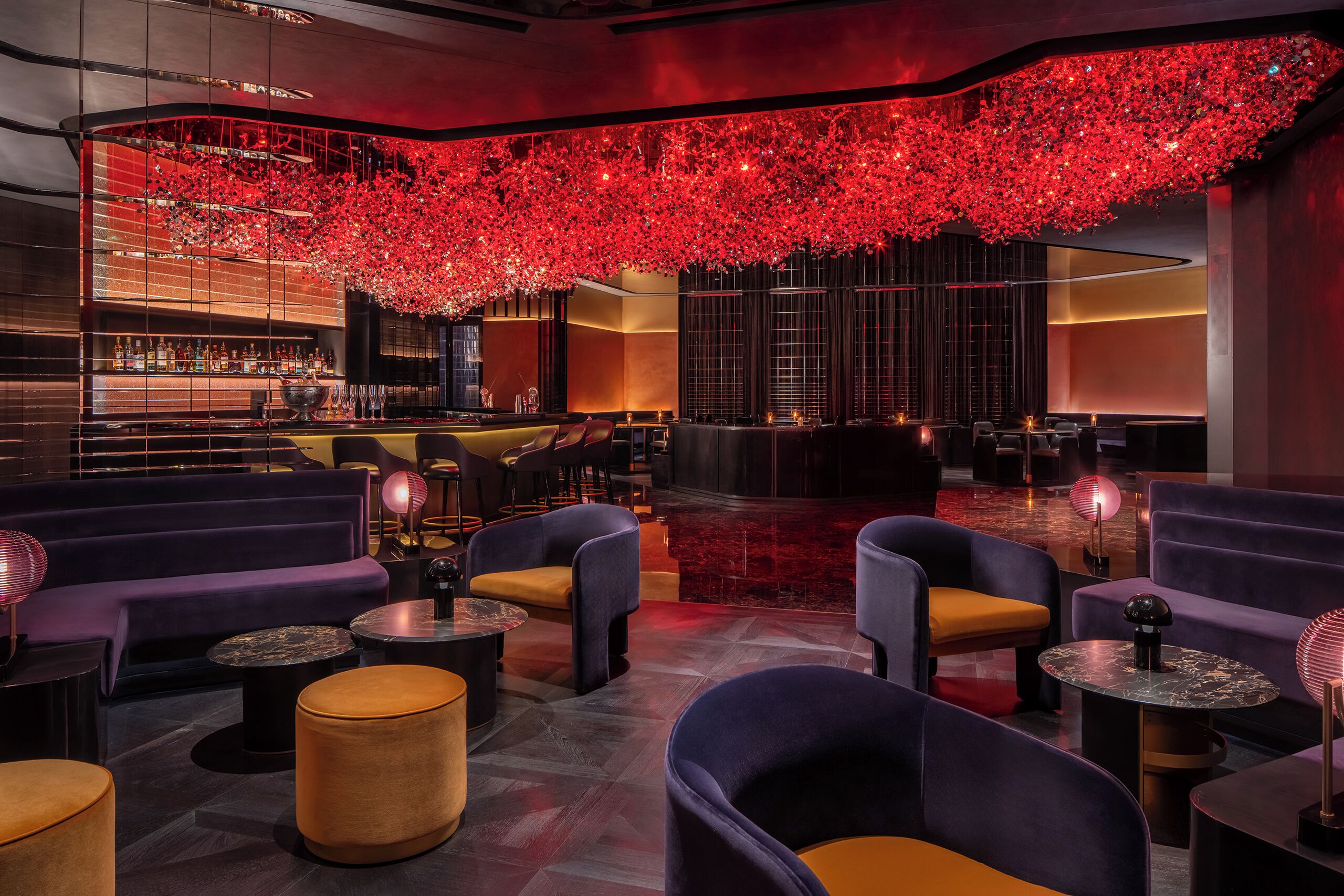 A modern lounge area with seating, a bar, and a decorative ceiling.