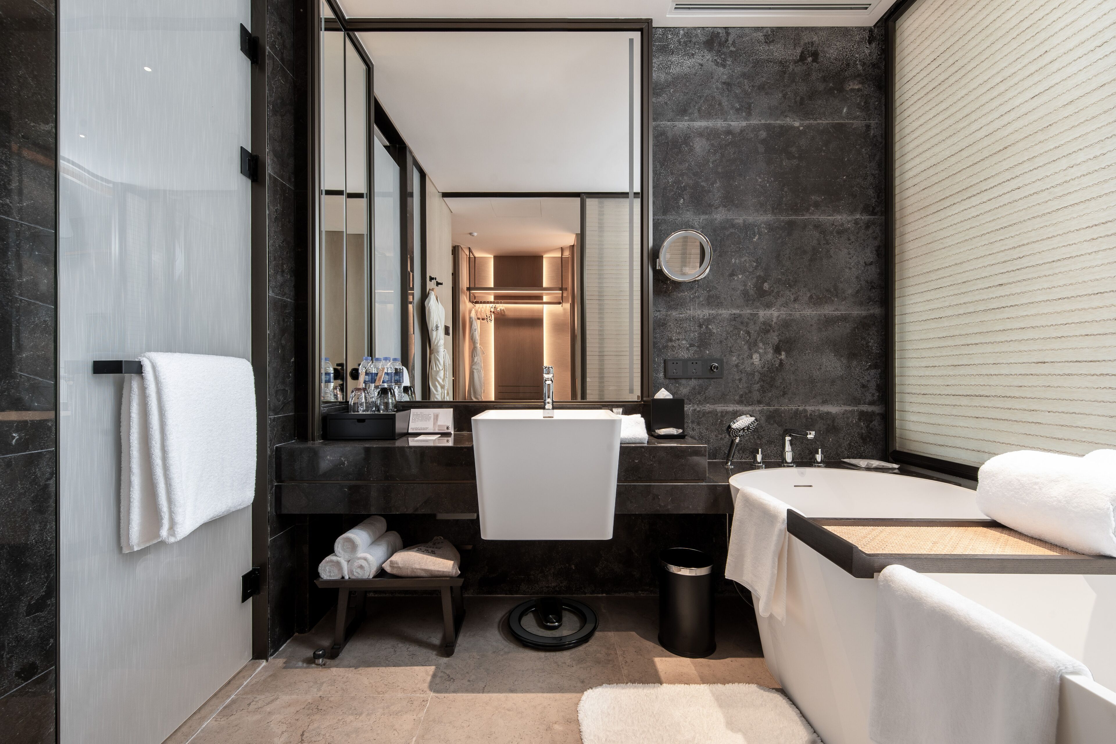 A modern bathroom with a large mirror, a bathtub, a sink, and a shower area.
