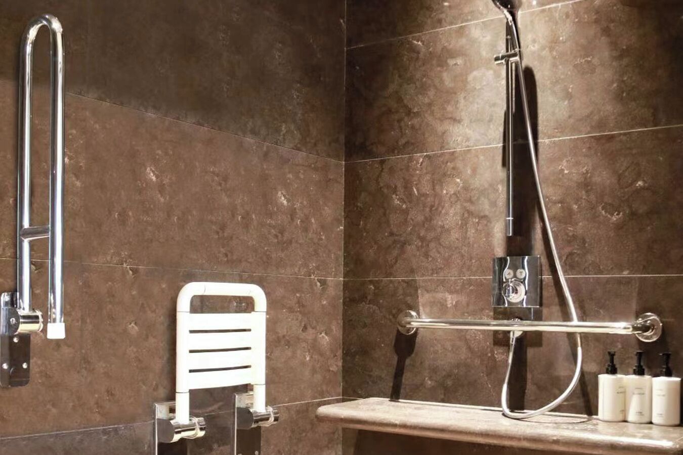A bathroom with a shower, grab bar, and a shelf with toiletries.