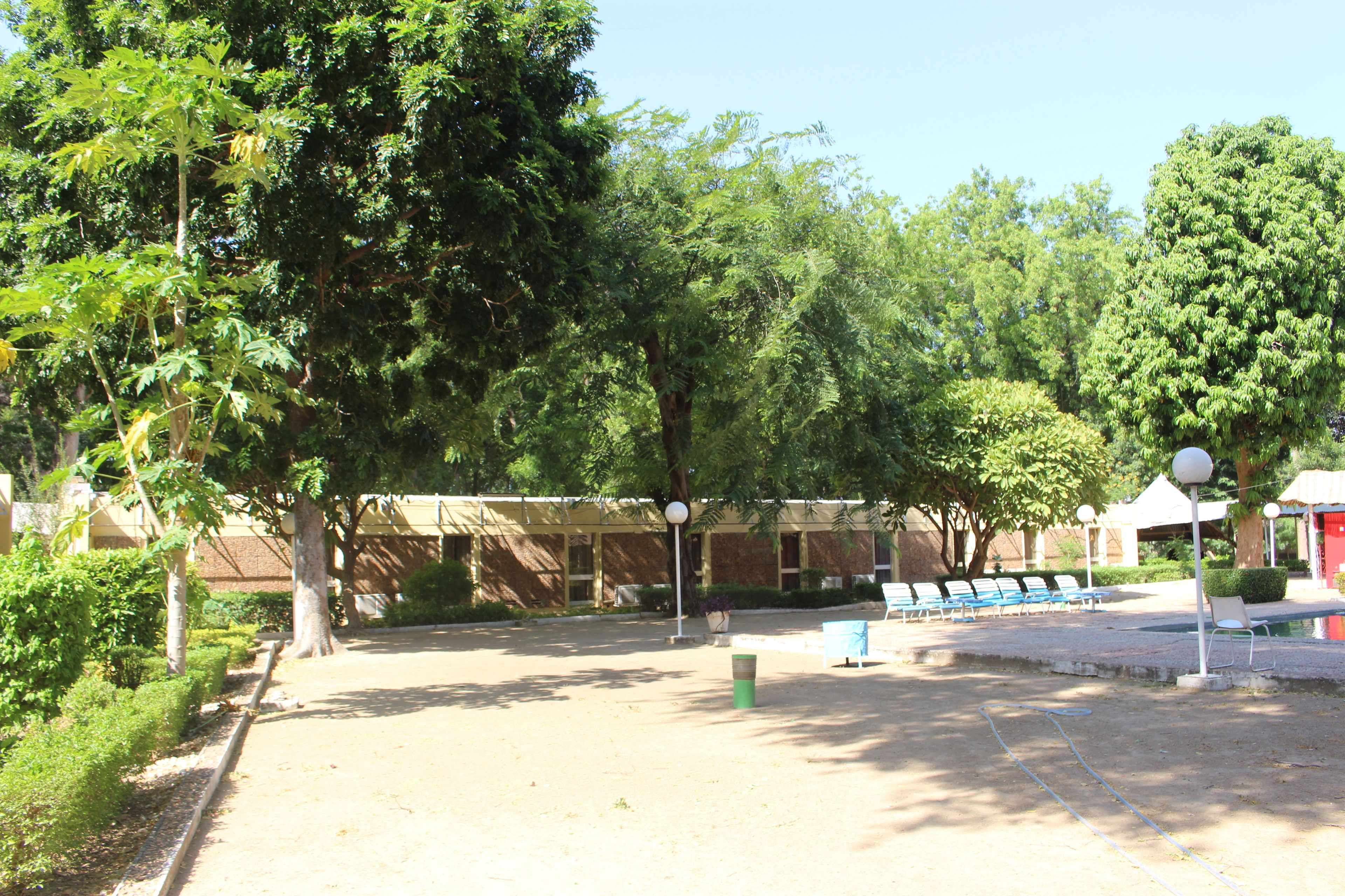Un patio con árboles, un edificio al fondo y mesas al aire libre.