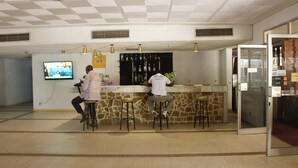 A bar area with stools, a television, and a wine rack. - Hotel Mizao (Maroua)