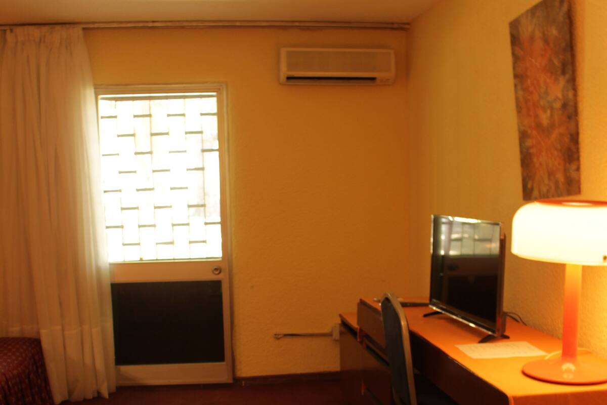 Escritorio, cortinas blackout y tabla de planchar con plancha
