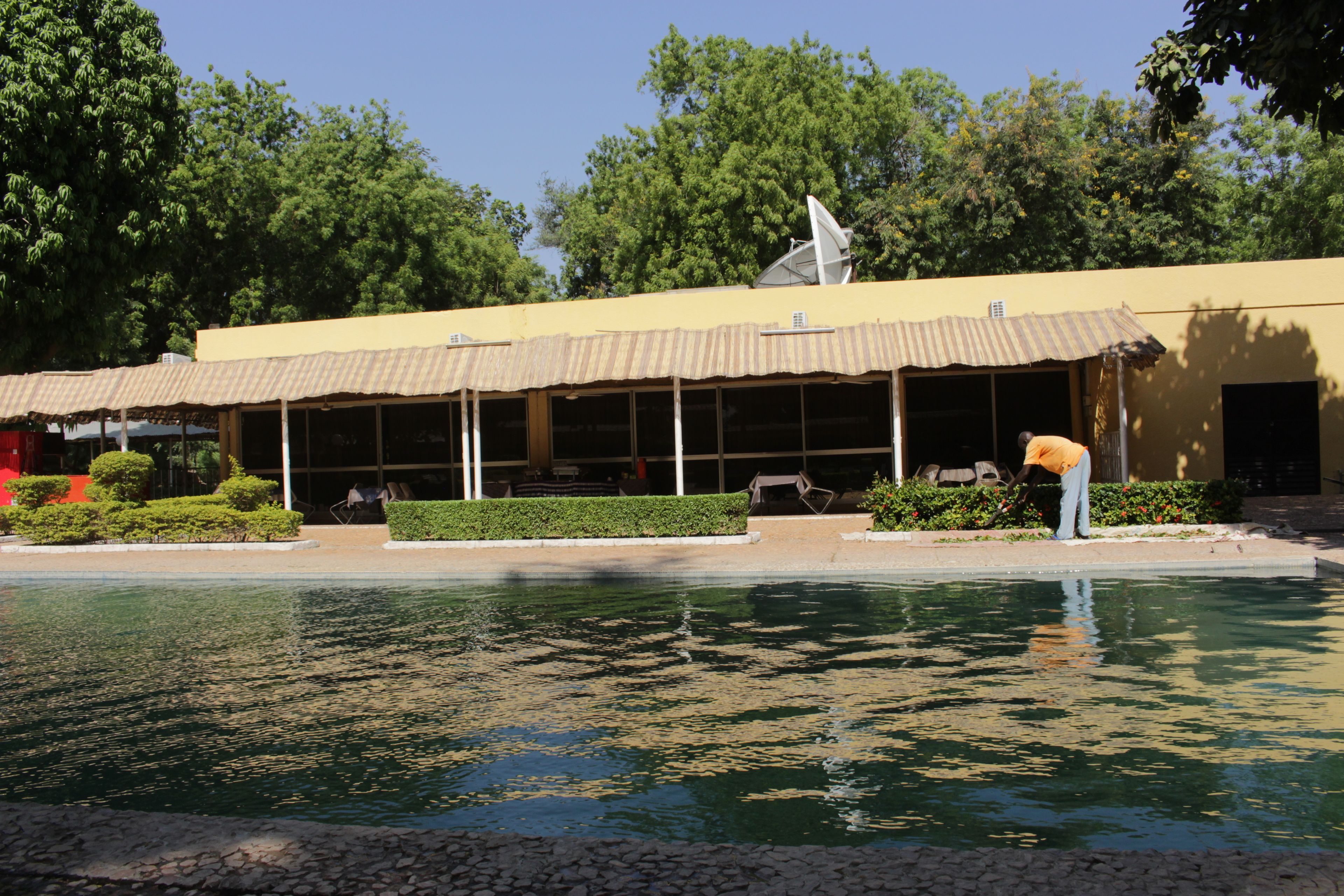 A building with a satellite dish, a covered outdoor area with benches, and a pool.