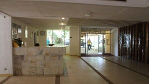 A reception area with a marble counter, a glass door entrance, and a patterned floor. - Hotel Mizao (Maroua)