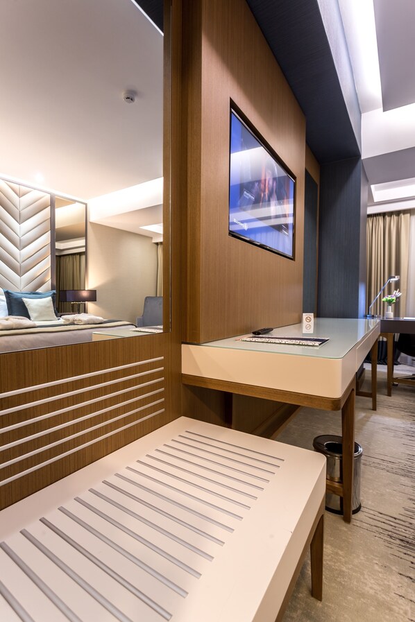 A hotel room with a bed, a desk, a television, and a trash can.
