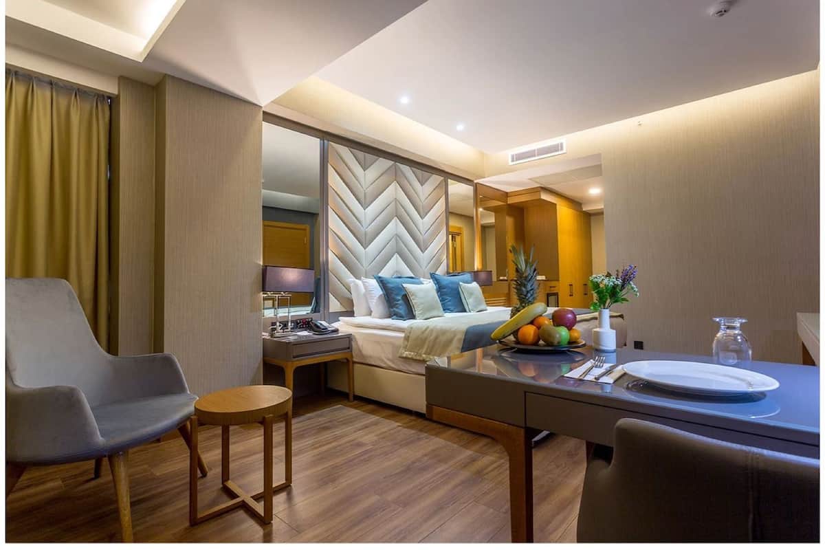 A modern hotel room with a bed, a desk, a chair, and a dining table.