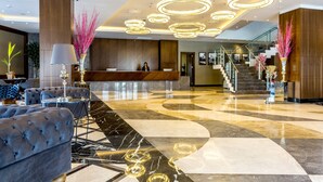 A modern lobby with a reception desk, plush seating, and a staircase. - Willmont Hotel (Balikesir)