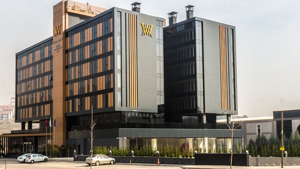A modern hotel building with a prominent 'W' logo, multiple floors, and a glass facade. - Willmont Hotel (Balikesir)
