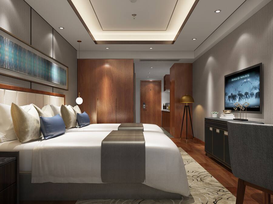 Quarto de hotel moderno com uma cama grande, uma escrivaninha com computador, uma televisão e um quadro grande na parede.