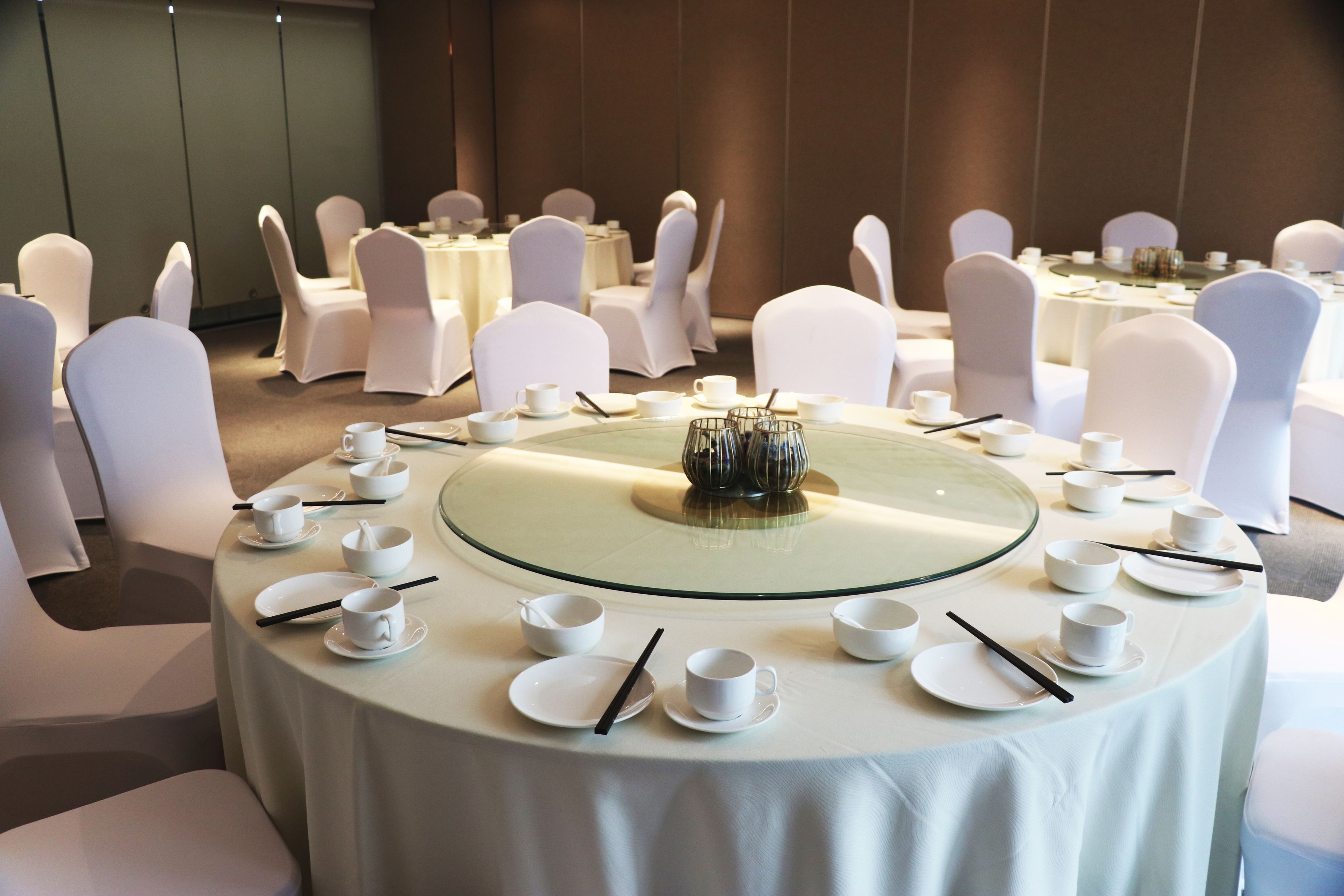 A conference room with round tables set for a meeting, equipped with white chairs and table settings.