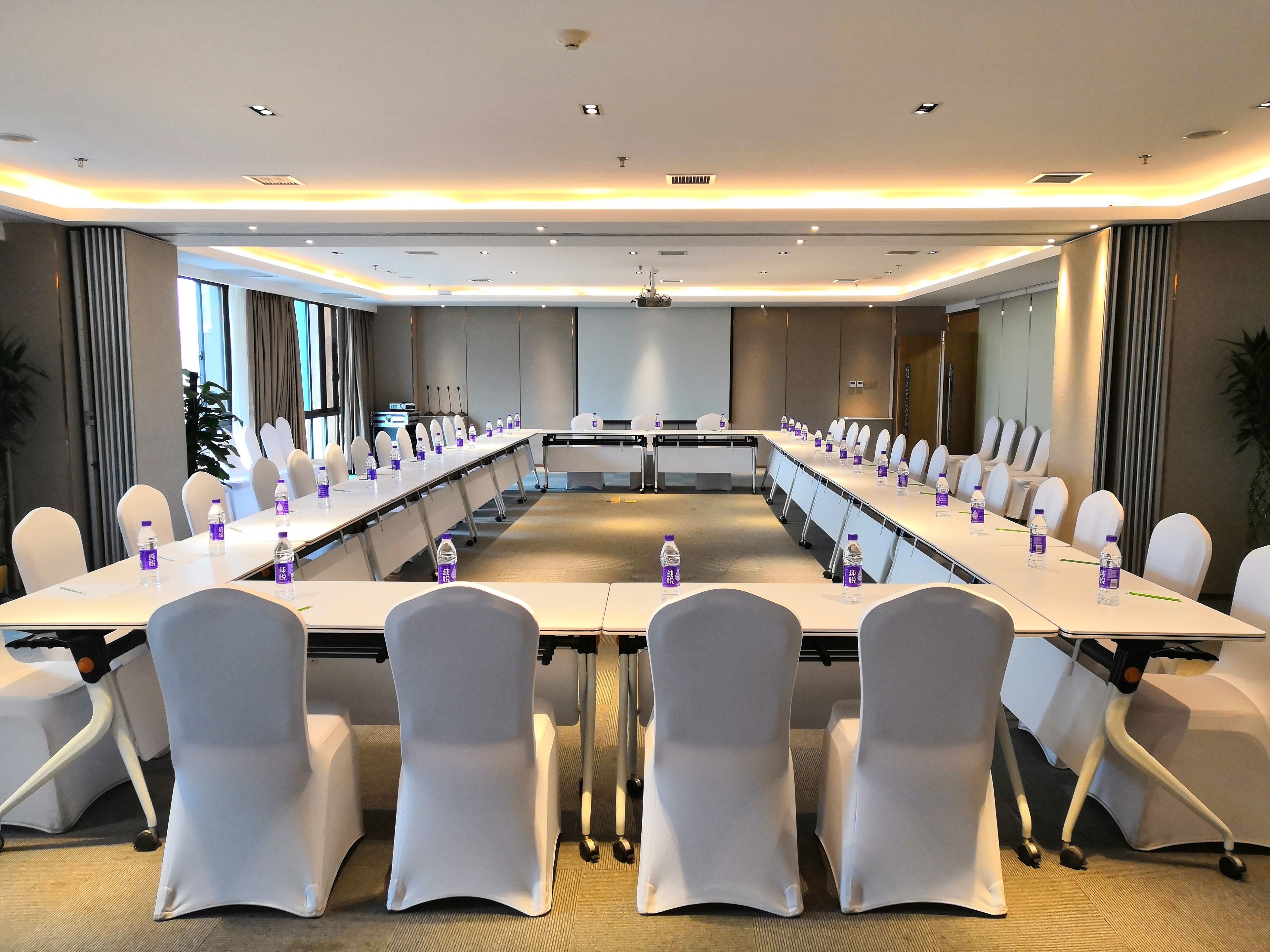 A conference room with a long table, white chairs, and water bottles.