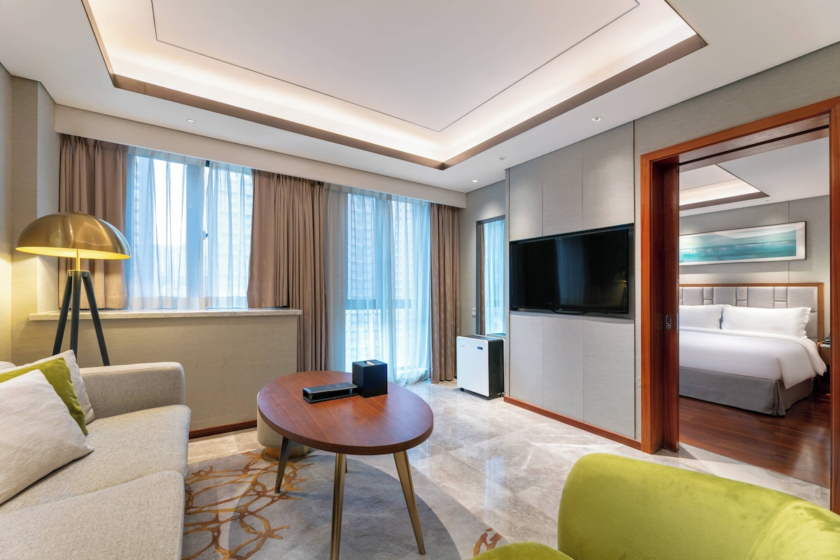 Een moderne hotelkamer met een bank, een ronde tafel, een televisie en een bed.