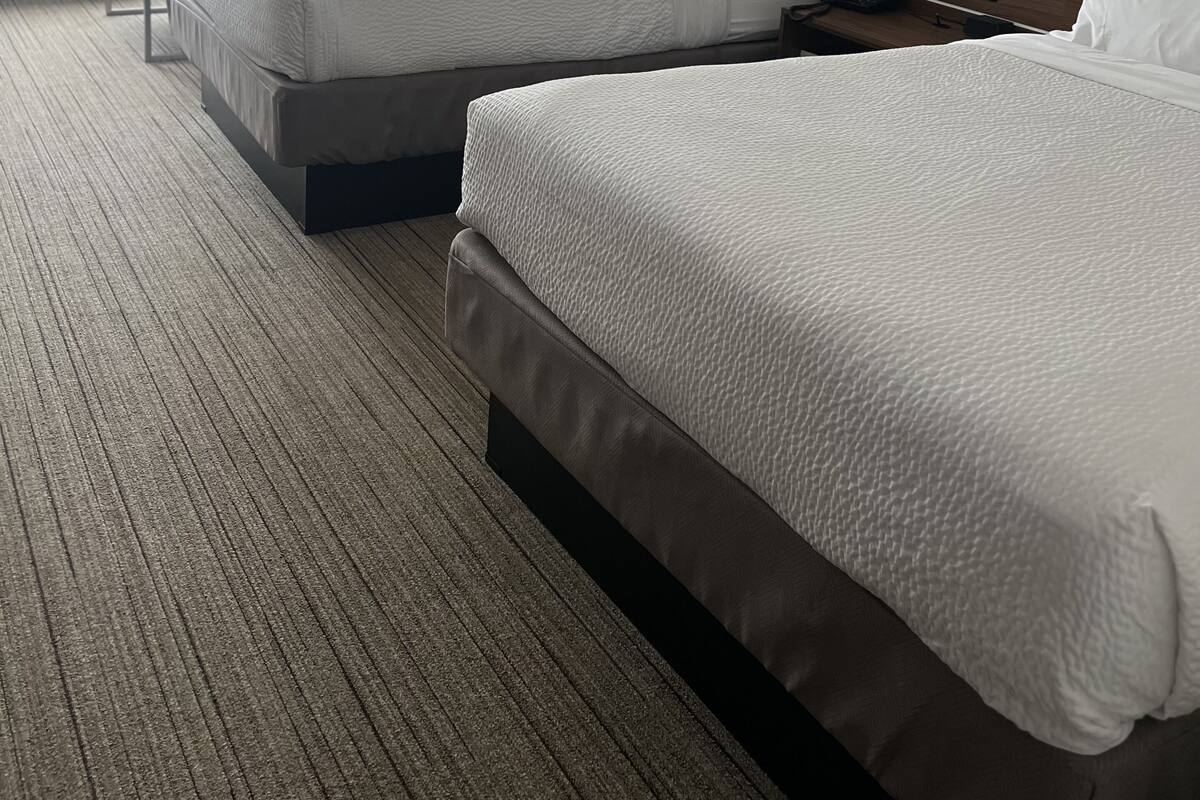A hotel room with two beds, a desk, and a window.