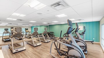 Un gimnasio con cintas de correr, elípticas y máquinas de pesas.