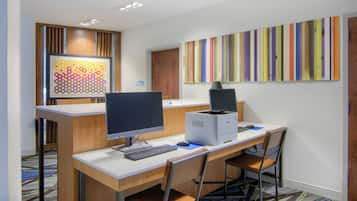 A modern office space with a desk, computer, and printer. There is a framed artwork on the wall and a sign indicating a mechanical room.
