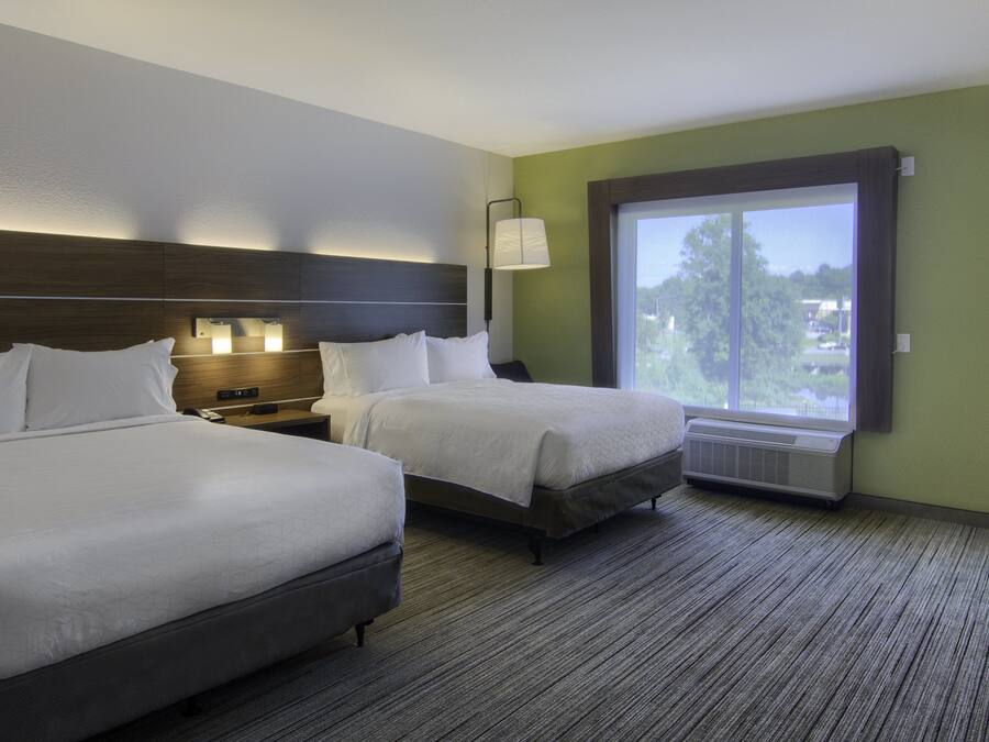 Habitación de hotel con dos camas, una mesita de noche, una lámpara, una ventana y vistas al exterior.