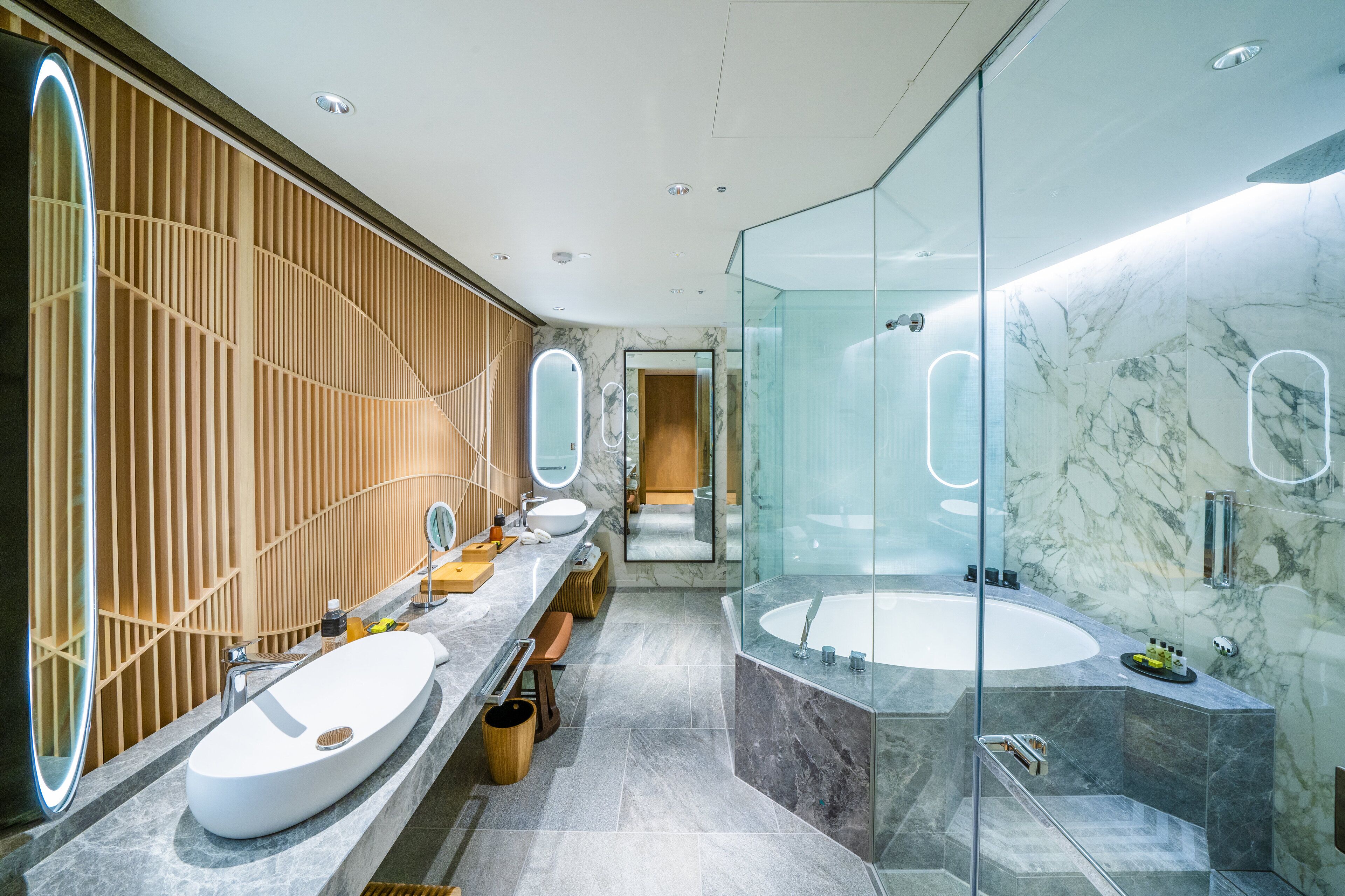 Un baño moderno con un tocador amplio, una bañera independiente y una zona de ducha con mampara de cristal.