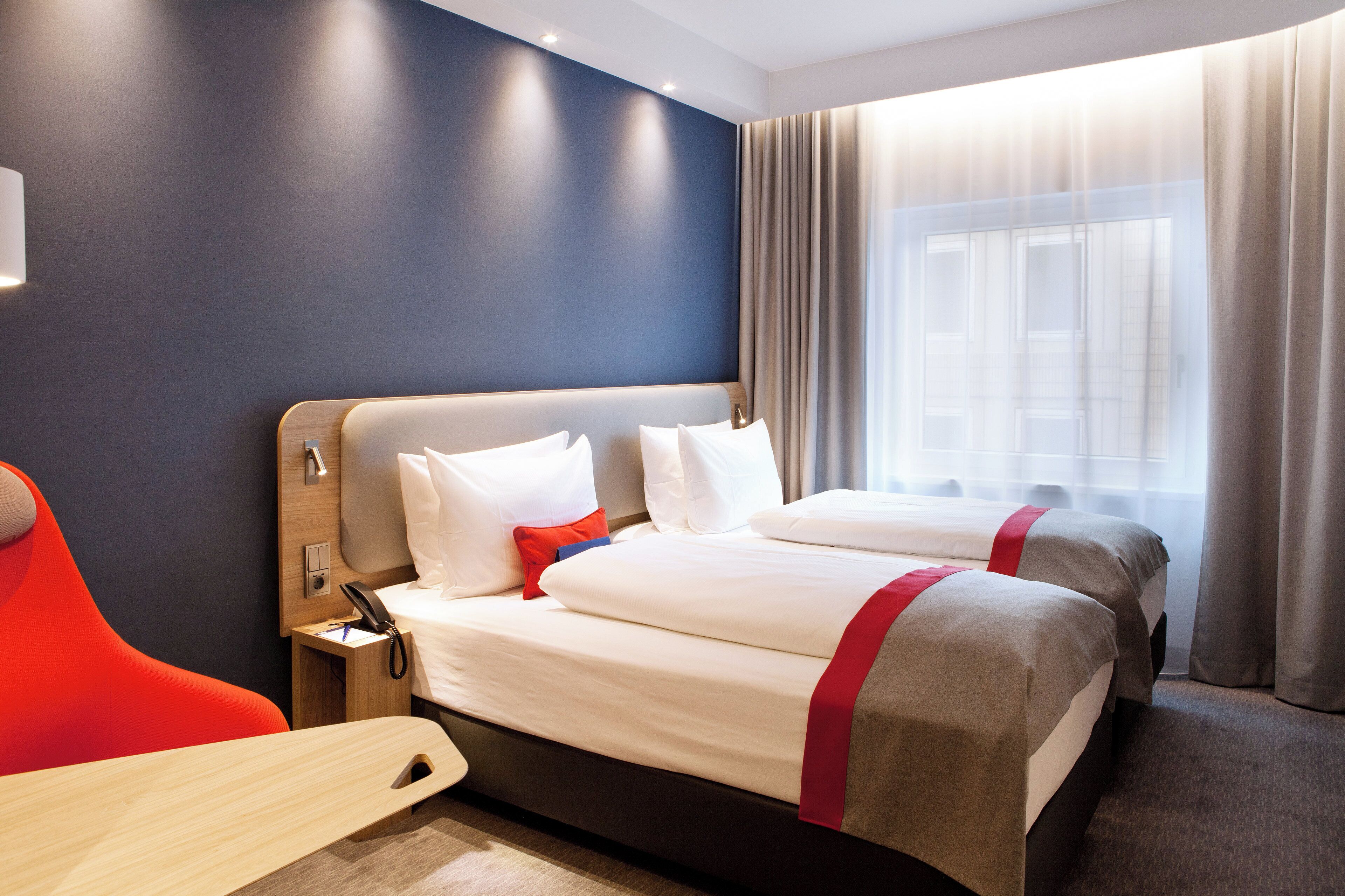 A hotel room with two beds, a desk, and a chair.