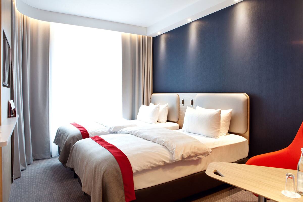 A hotel room with two beds, a desk, and a chair.