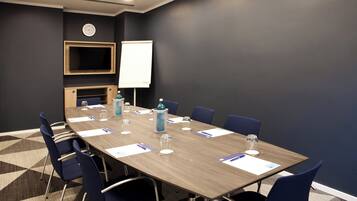A conference room with a long table, chairs, a clock, and a whiteboard.