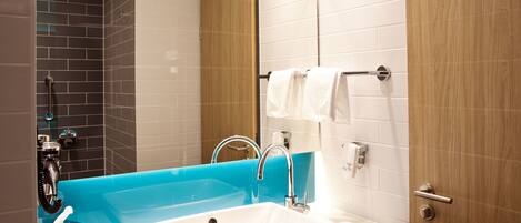Une salle de bain moderne avec un grand lavabo blanc, une baignoire bleue et une porte en bois.