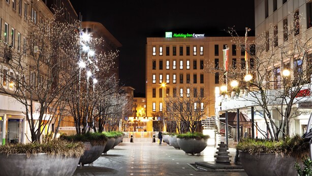 A nighttime urban square with a Holiday Inn Express building in the background.