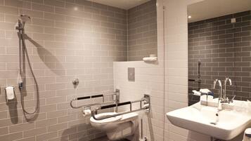 Ein modernes Badezimmer mit grauen Fliesen, einem weißen Waschbecken und einer Handbrause.