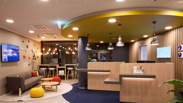 A modern hotel lobby with a reception desk, seating area, and a flat-screen TV. - Holiday Inn Express Mulheim - Ruhr by IHG (Muelheim an der Ruhr)