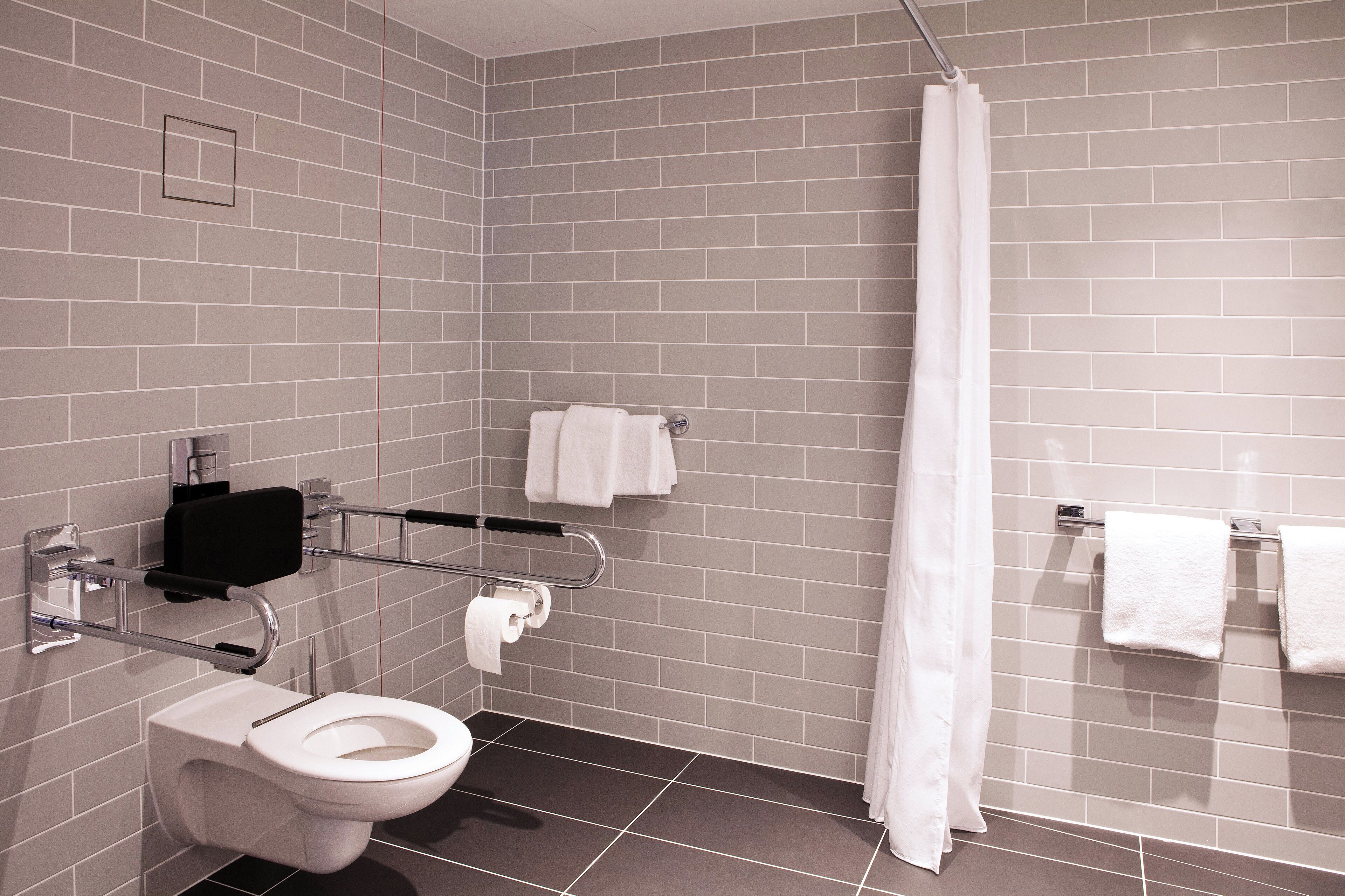 A modern bathroom with a toilet, hand dryer, and towel rack.