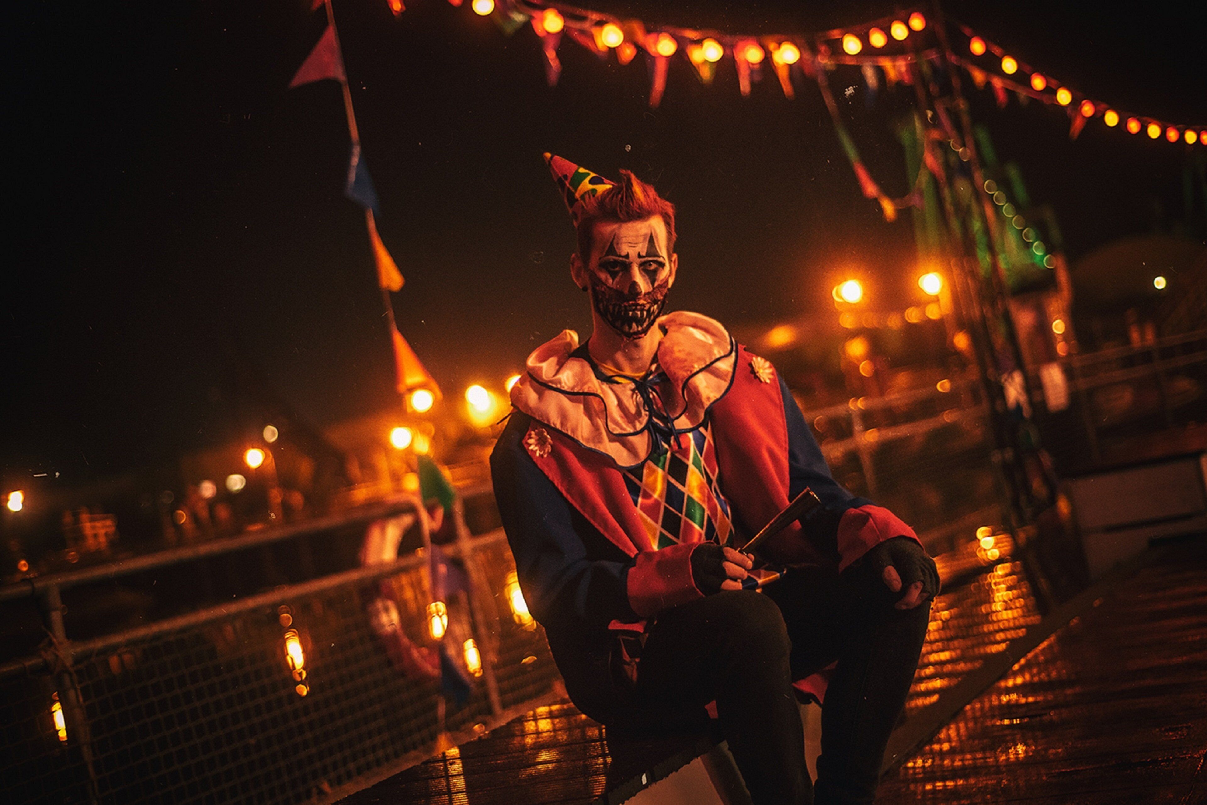 A person sitting on a bridge with string lights in the background.