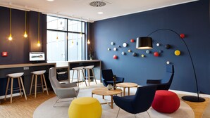 A modern office space with a round table, chairs, and a TV on a desk.