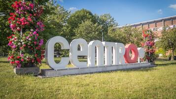 Un gran letrero exterior con la palabra 'CENTRO' en letras blancas, rodeado de follaje exuberante y plantas con flores.
