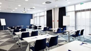 Un salón de conferencias con mesas, sillas y pizarras.