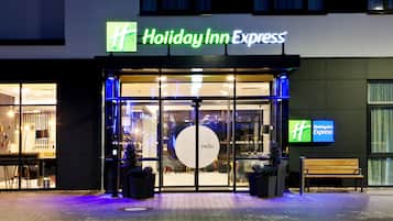 Das äußere Erscheinungsbild eines Holiday Inn Express Hotels mit einem großen Glas Eingangsbereich, einer Bank davor und einem Weihnachtsbaum.