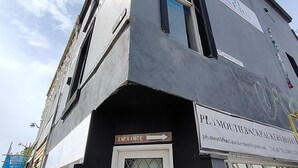 Un edificio con un cartel que dice "Plymouth Backpack Packers Hotel" y una señal de entrada.