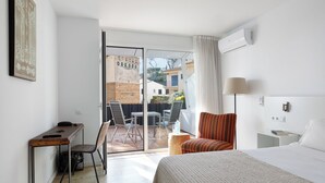 Hotelkamer met een bed, een bureau, een stoel, een lamp en uitzicht op buiten.