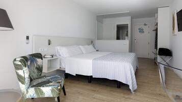 Een moderne hotelkamer met een bed, een stoel, een bureau en een kledingkast.