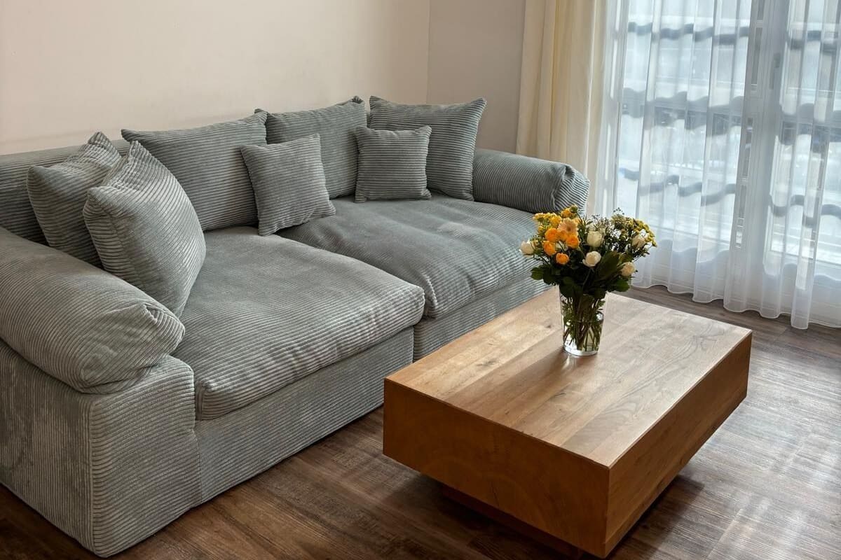 A living room with a sectional sofa, a wooden coffee table, and a floral arrangement.