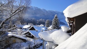 Un pueblo cubierto de nieve con casas tradicionales, montañas al fondo y cielo despejado.