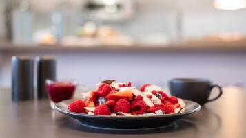 Un plato de frutos rojos y nueces sobre una mesa con fondo desenfocado.