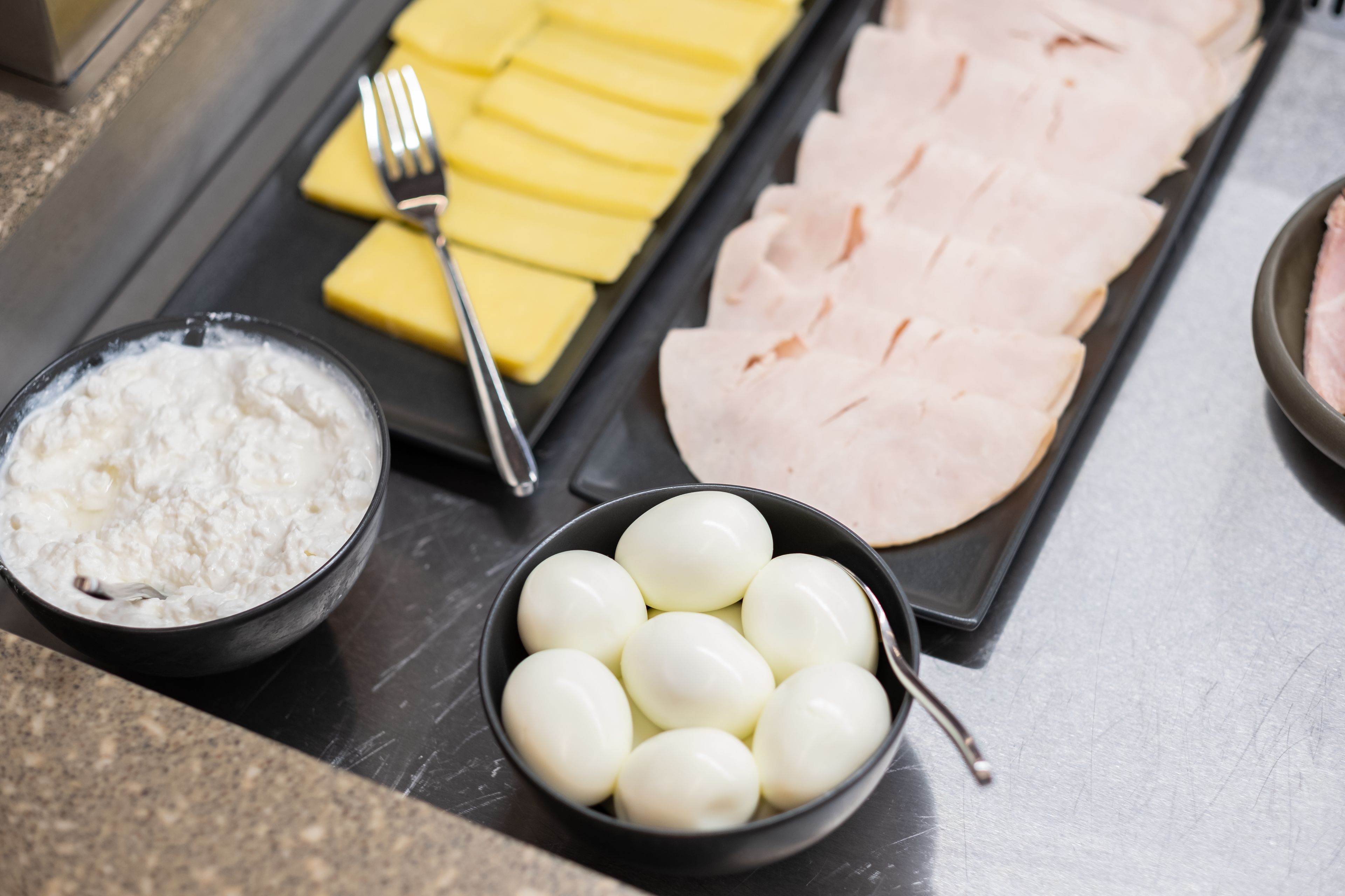 Uma bandeja com presunto fatiado, queijo e ovos cozidos sobre uma mesa.