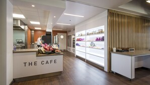 Café com balcão de recepção, cozinha e vitrine com lanches.