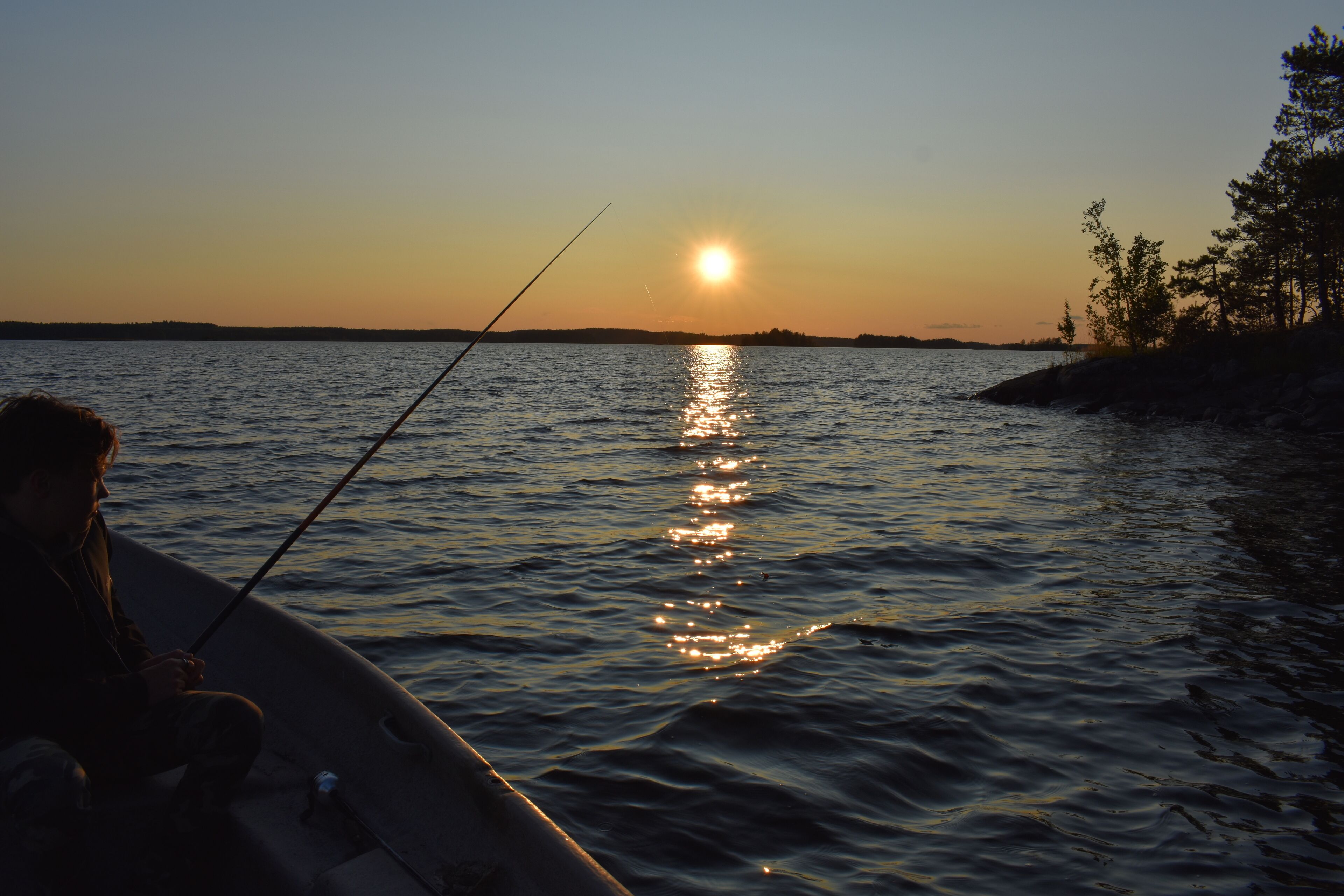 A boat on calm water with a person fishing.