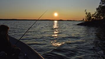 A boat on calm water with a person fishing.