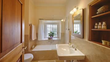 A bathroom with a bathtub, a sink, and a toilet. There is a window with a view of greenery outside.